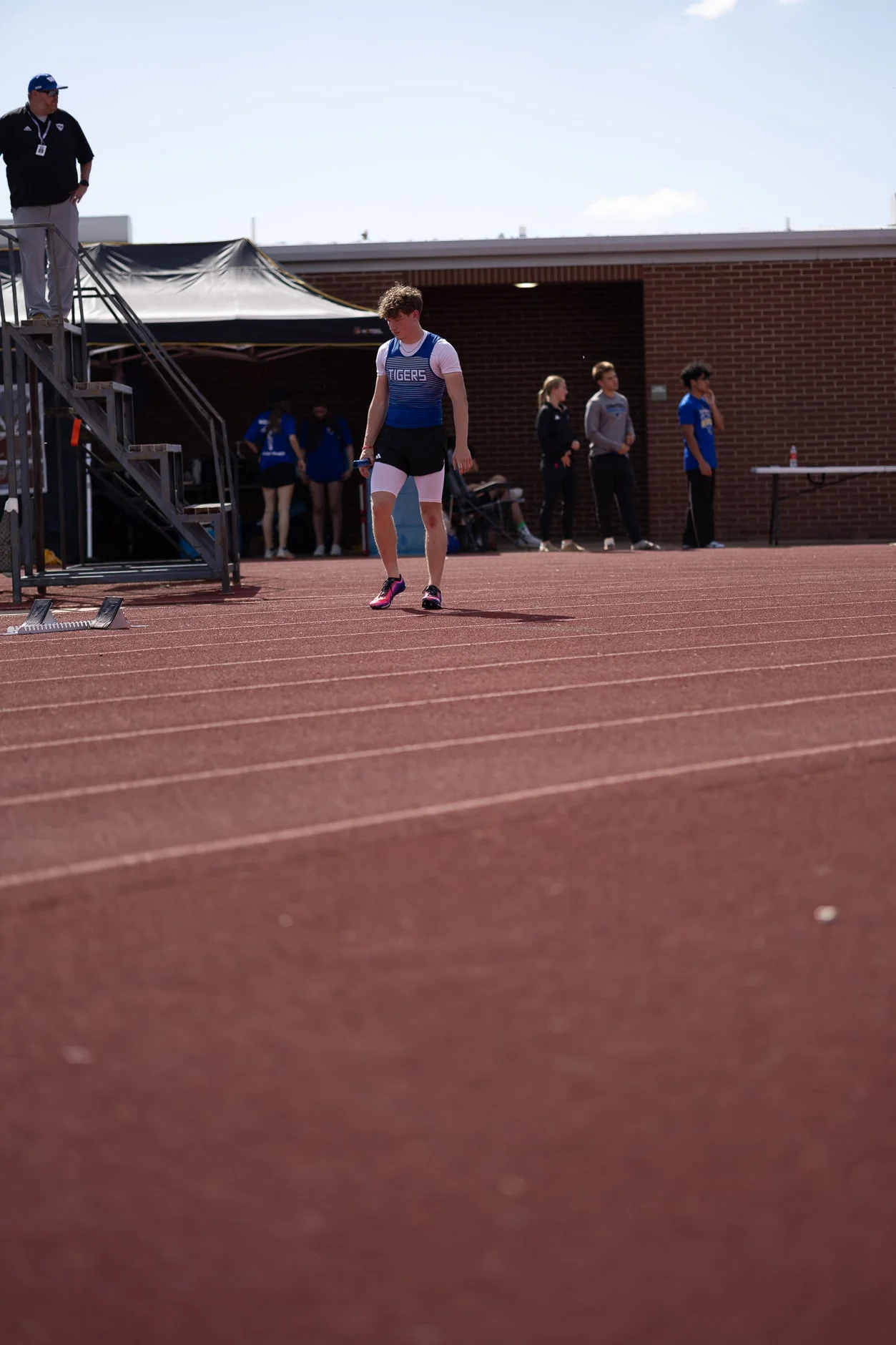 A Tigers athlete in a singlet walking the track between events, straight off the camera