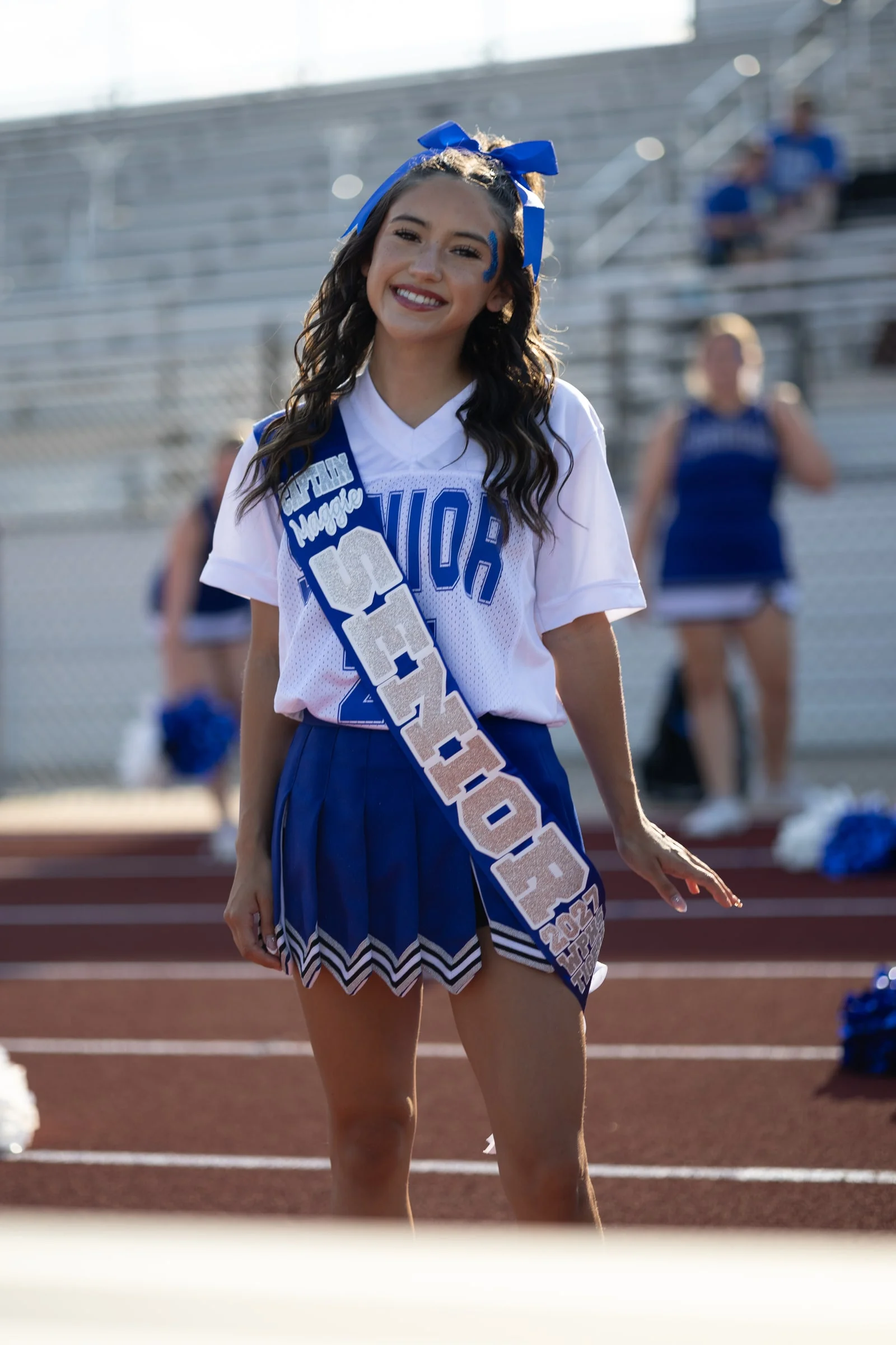 The cheer captain in her senior night sash on the track, straight off the camera