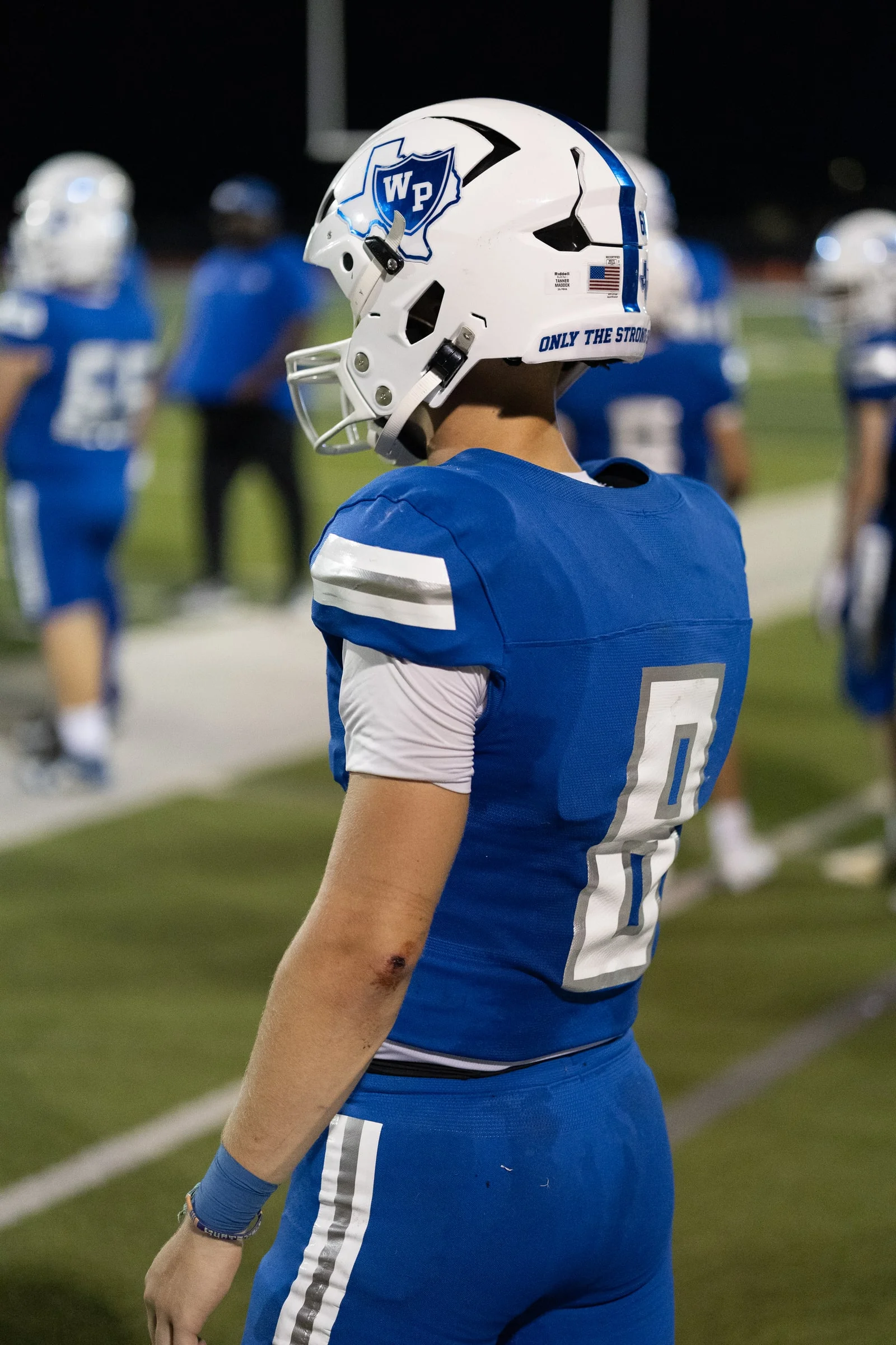 Number 8 from behind on the sideline, helmet catching the stadium lights, straight off the camera